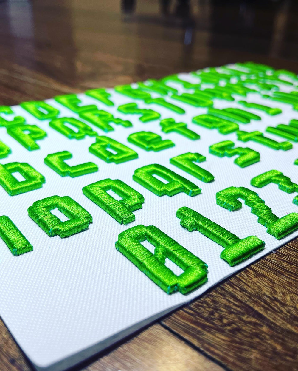 Green letters and numbers on a white mat with a wooden floor background