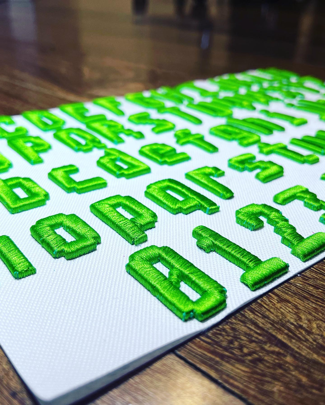 Green letters and numbers on a white mat with a wooden floor background