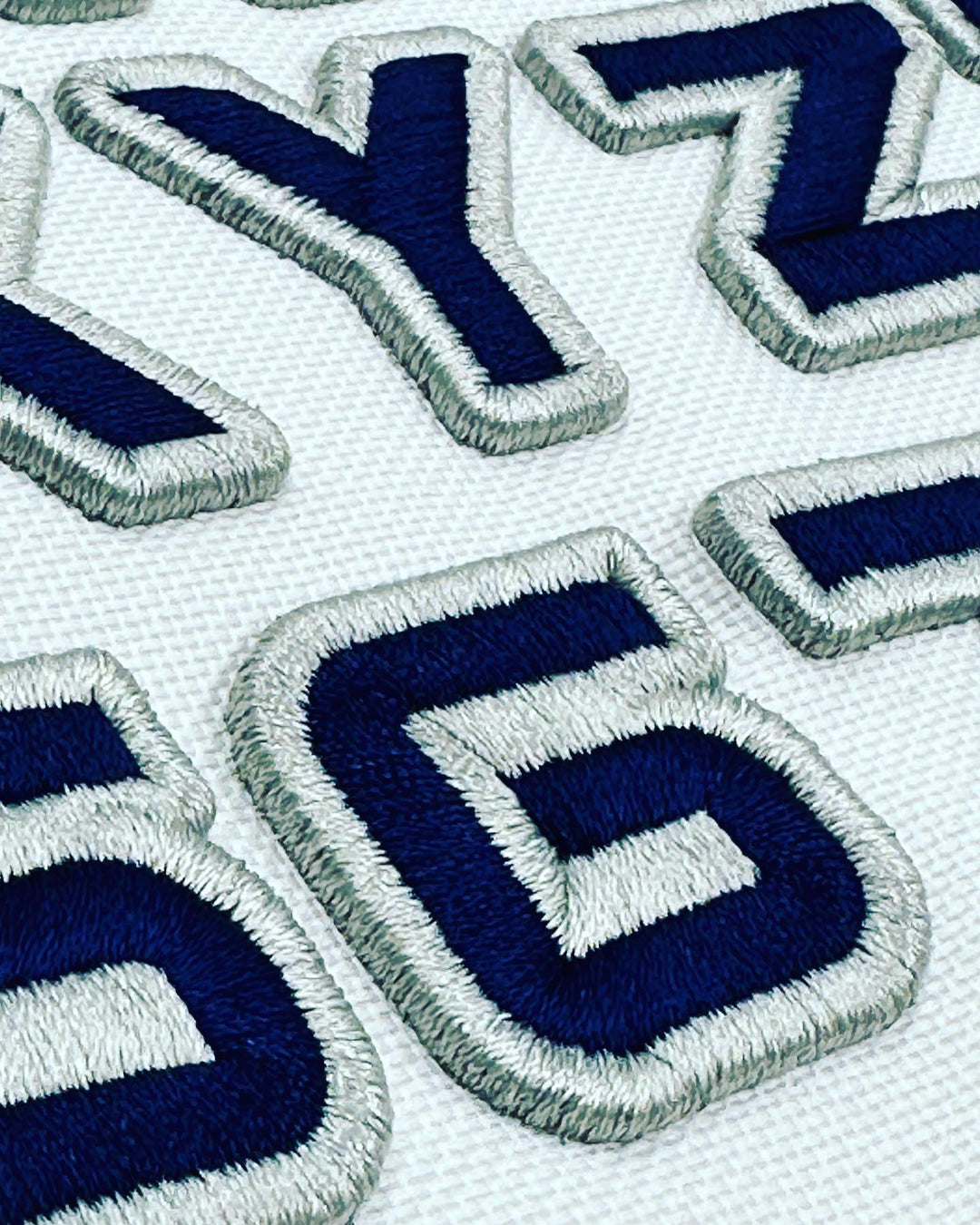 Close-up of embroidered blue and white letters on a fabric background