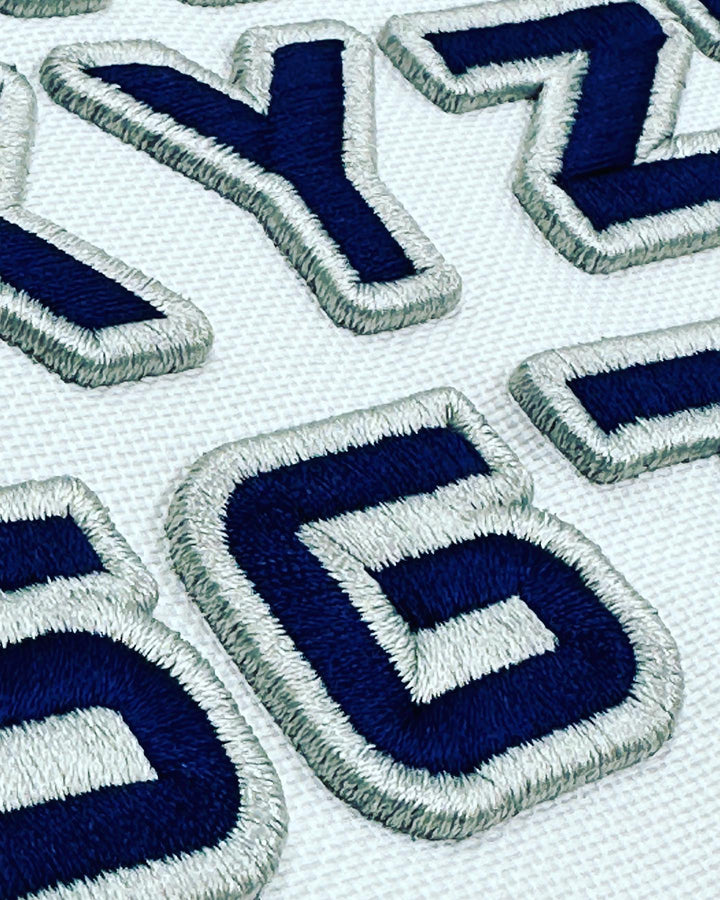 Close-up of embroidered blue and white letters on a fabric background