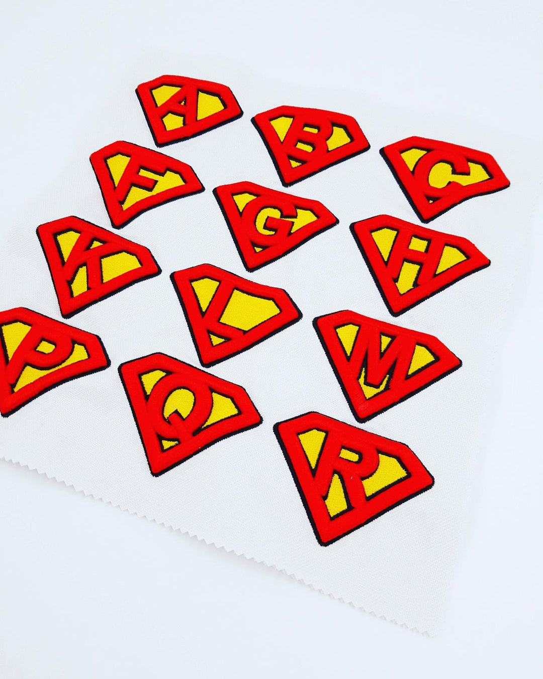 Red and yellow superhero logo patches arranged on a white background