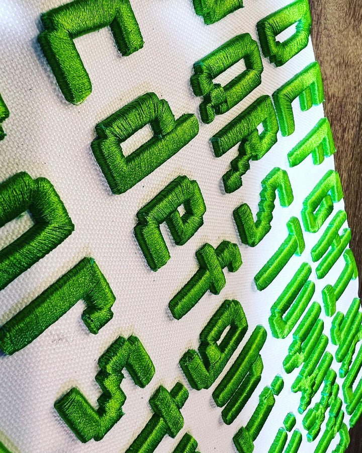 Green embroidered letters on a white fabric background