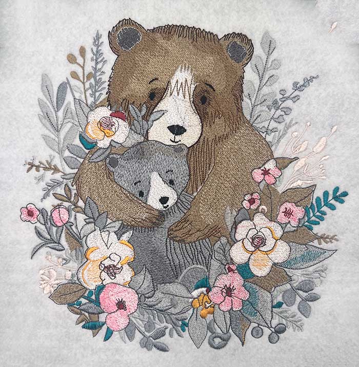 Embroidered image of a mother bear and her cub surrounded by floral patterns .