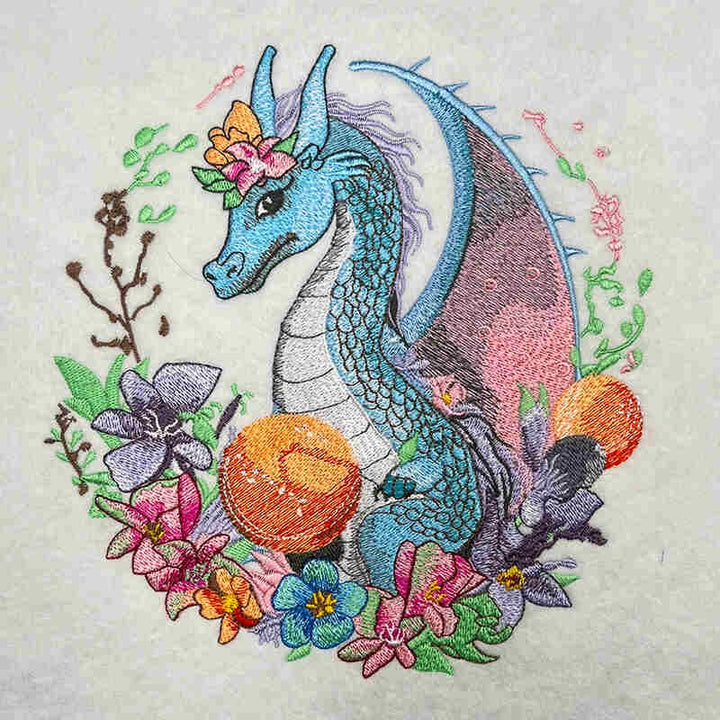 Embroidered design of a dragon surrounded by flowers on fabric.