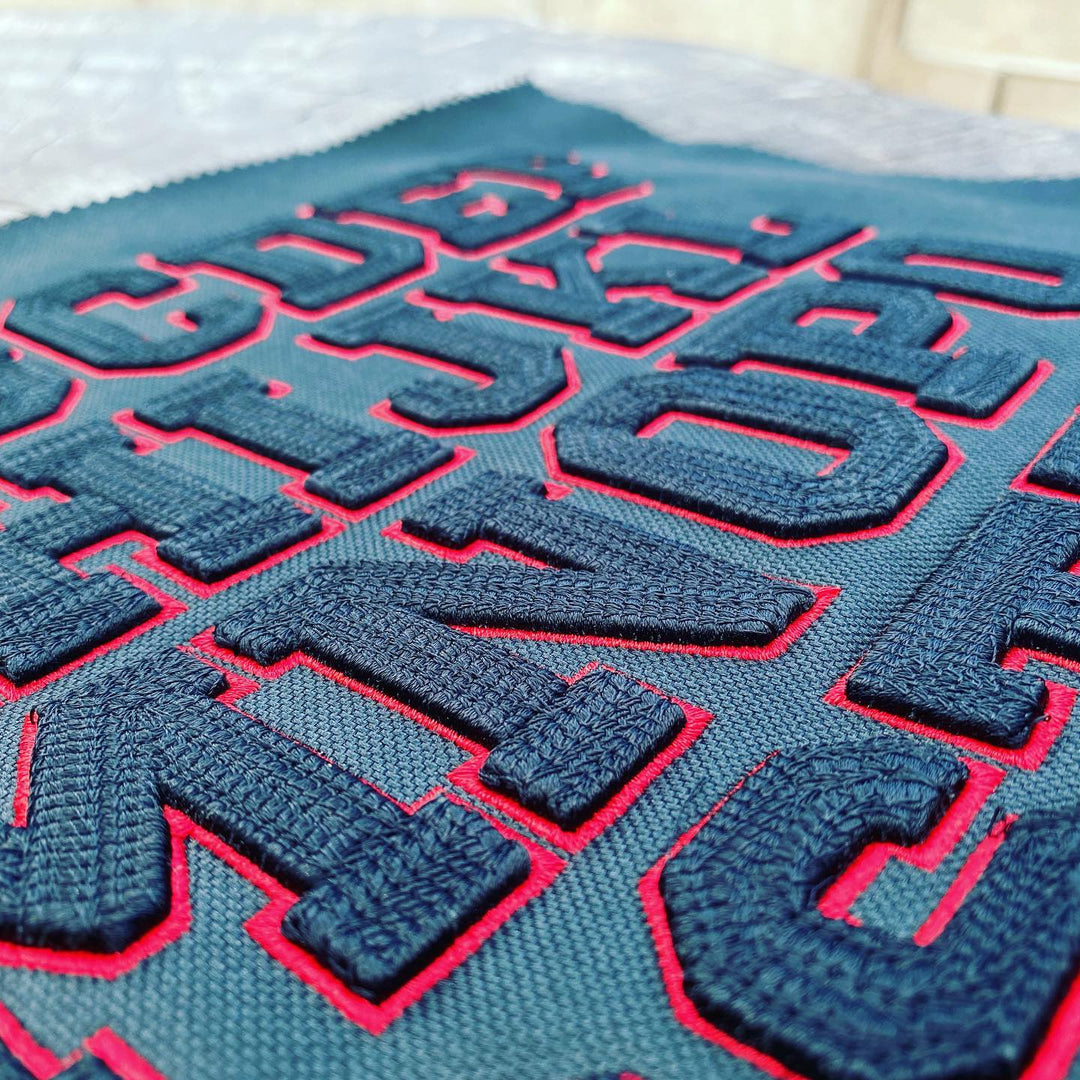 Close-up of a textured fabric with embroidered letters on a flat surface.