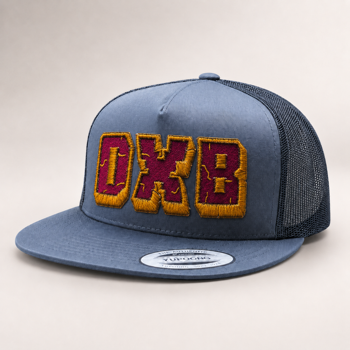 Blue trucker cap with embroidered letters on a light gray background