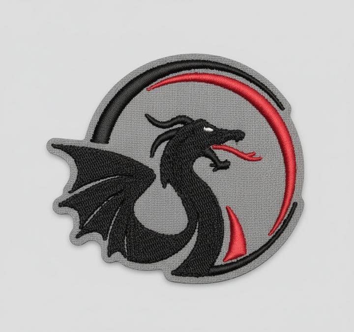 Black dragon embroidery patch featuring a sleek dragon silhouette with wing and red tongue inside a gray circular crest with red and black arc accents, stitched on a light background, original EmbroMania artwork.