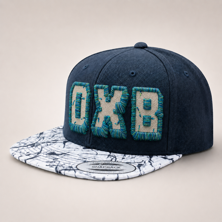Navy blue cap with textured white and green text on a marble-patterned brim against a beige background