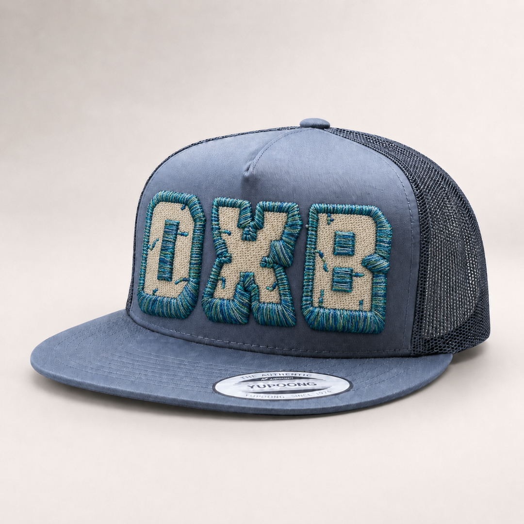 Blue trucker cap with embroidered letters on a light gray background