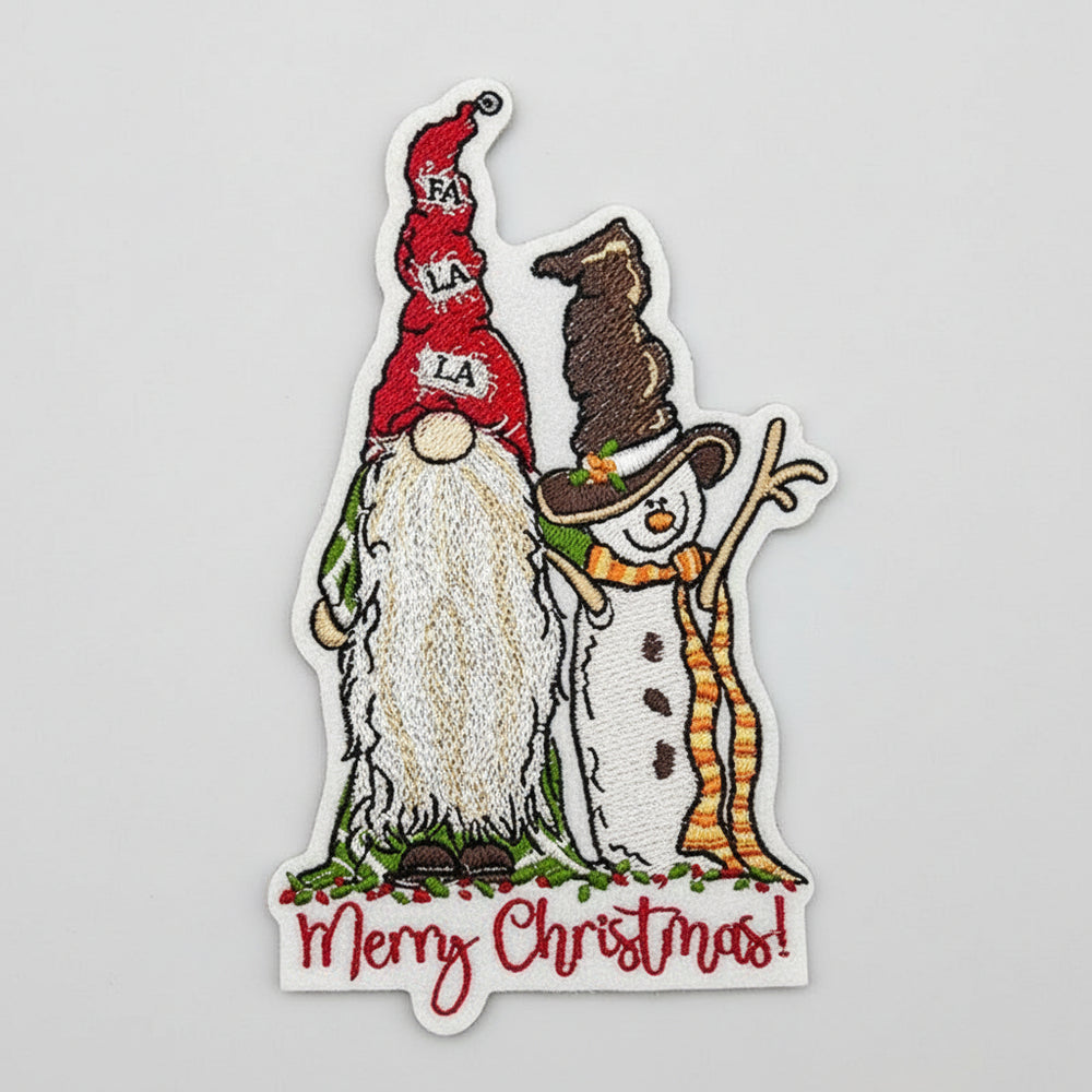 Close-up of embroidered gnome and snowman with “Merry Christmas!” text on white fabric.