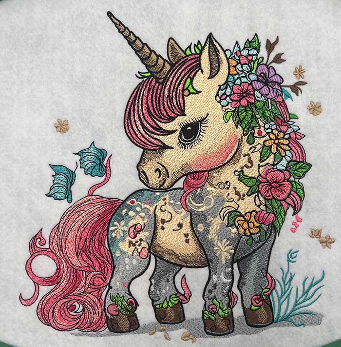Colorful embroidered design of a unicorn with floral decorations on a white background