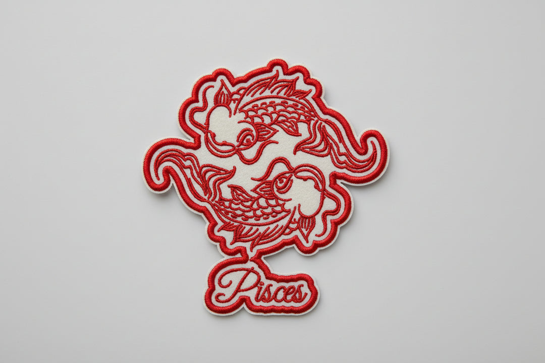 Pisces zodiac fish embroidery patch featuring two stylized fish circling in red outline stitching and the word “Pisces” in script below, on a light background, original EmbroMania artwork.