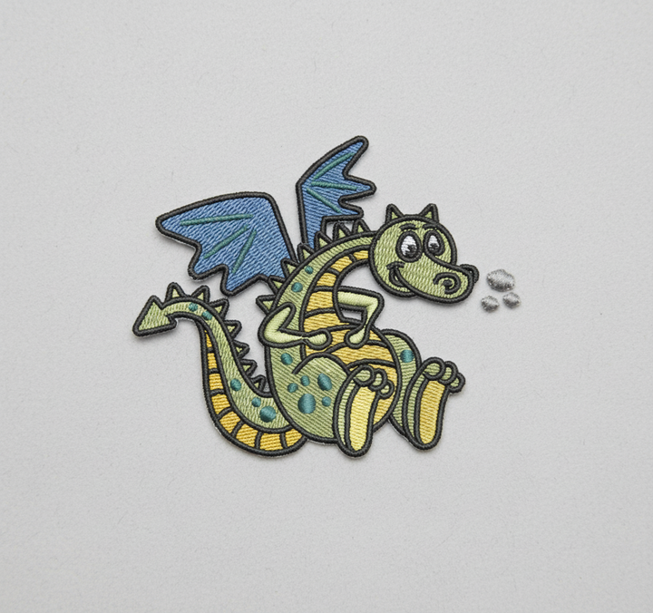 Cute baby dragon embroidery patch featuring a smiling green dragon with blue wings, yellow belly stripes, and teal spots, stitched with bold black outline on a light background, original EmbroMania artwork.