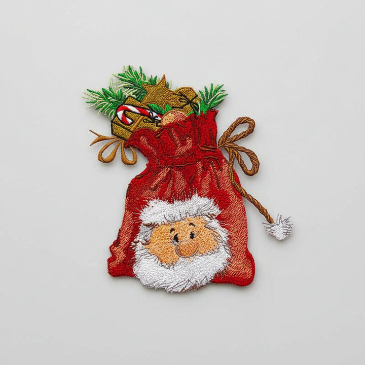  Close-up of embroidered red gift sack filled with presents and pine sprigs, featuring a smiling Santa face on white fabric.