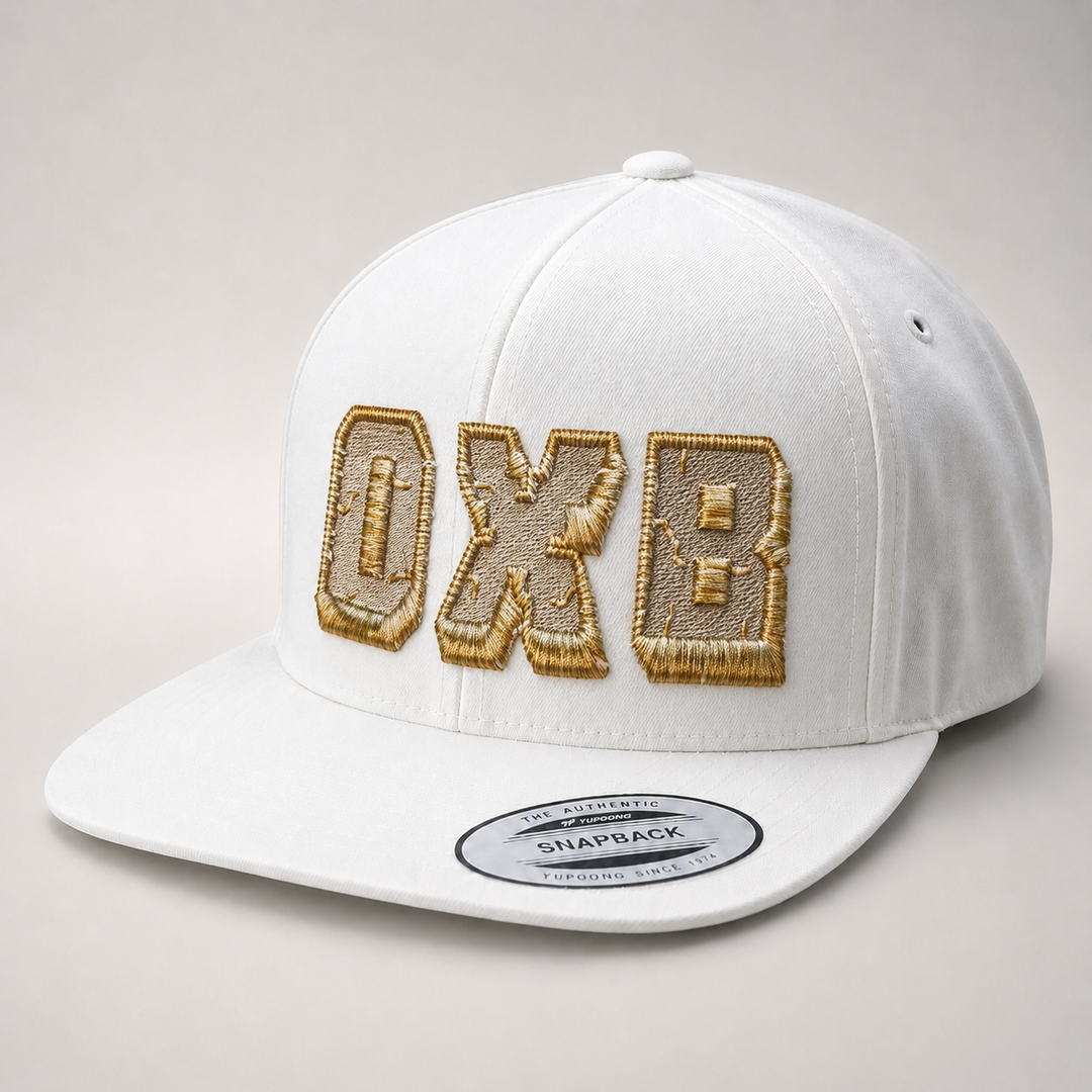 White cap with gold embroidered letters on a gray background
