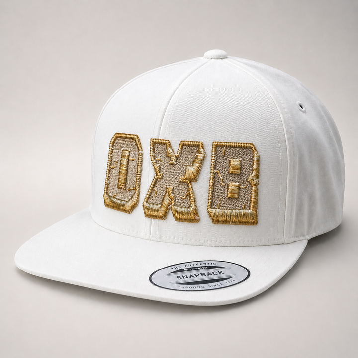 White cap with gold embroidered letters on a gray background