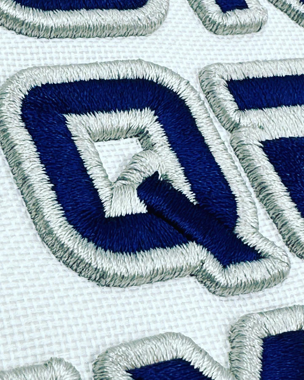 Close-up of embroidered blue and white patches with a geometric design.