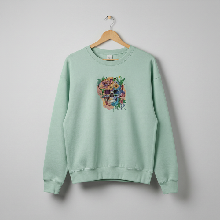 Mint green sweatshirt with a colorful skull design on a hanger against a gray background