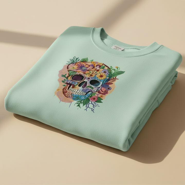 Folded light blue sweatshirt with a colorful skull design on a beige background