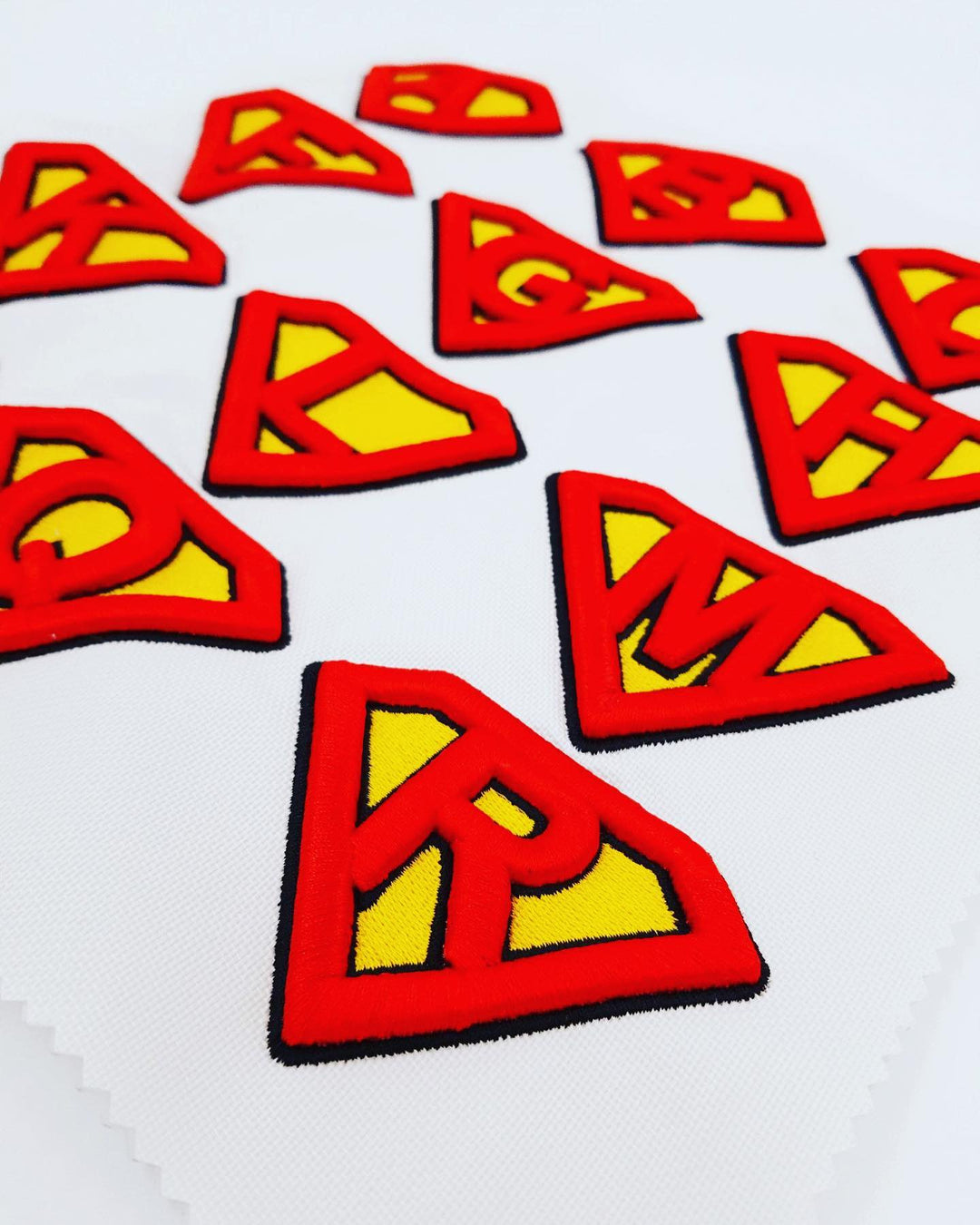 Red and yellow superhero logo patches on a white background