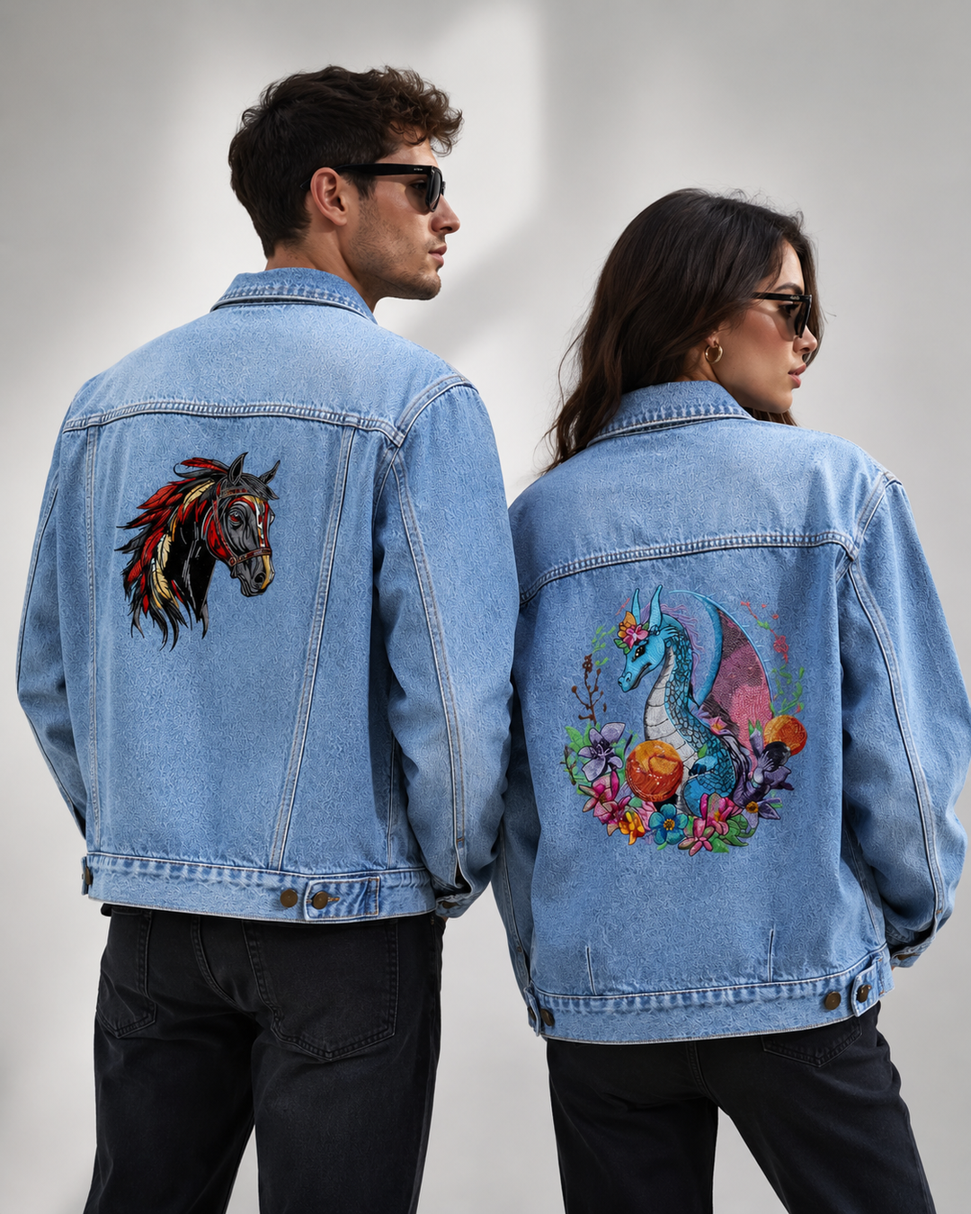 Two people wearing denim jackets with embroidered designs on a plain background