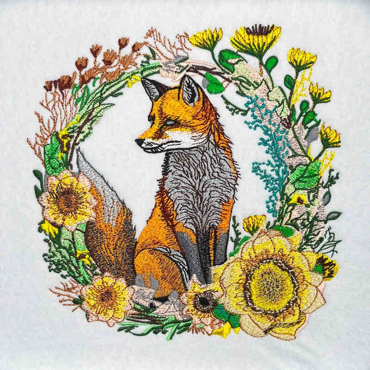 Embroidered design of a fox surrounded by flowers on a white background