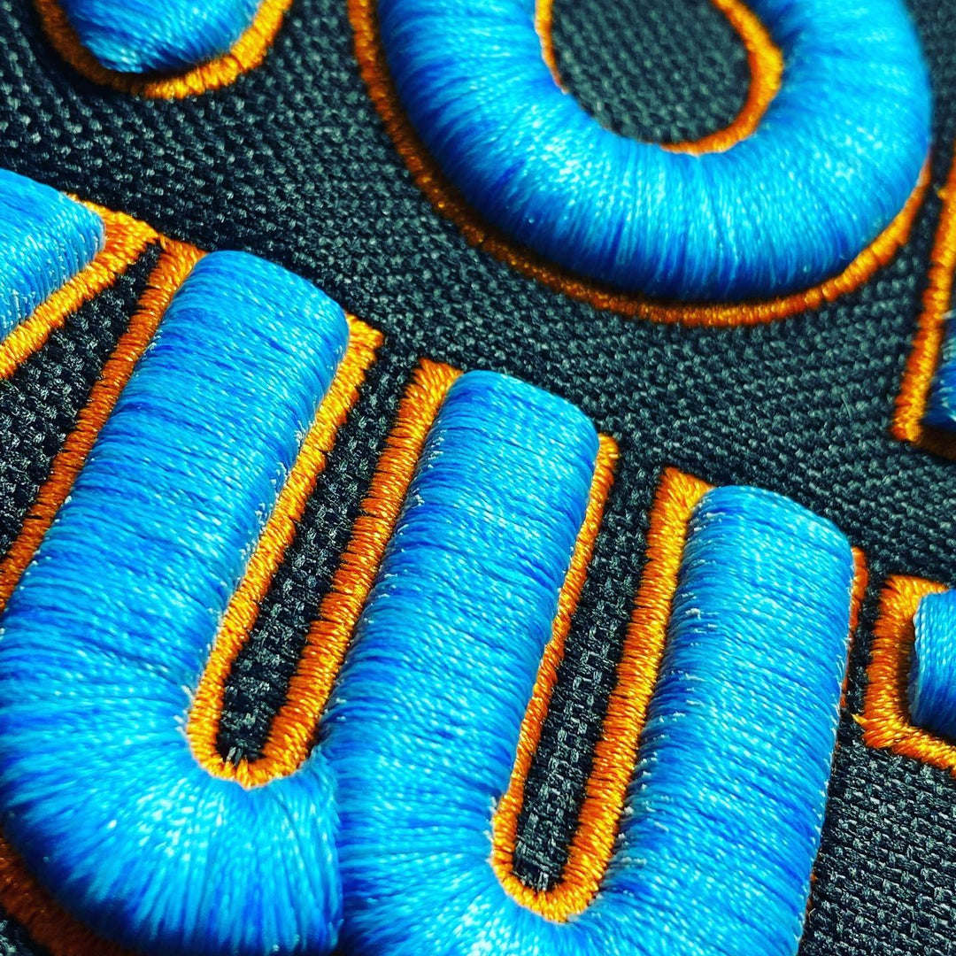 Bubble Pop 3D Puff – Extreme Dimensional Height Close-Up · Royal Blue fill · Gold outline · Machine Embroidered on Dark Fabric | Hand Finished in Dubai | EmbroMania